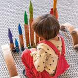 Child playing with the Grimm's large wooden building rollers in natural.
