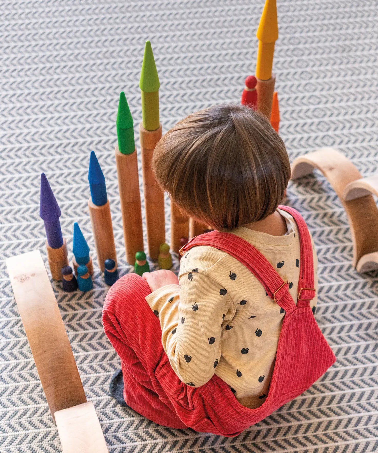 Child playing with the Grimm's large wooden building rollers in natural.