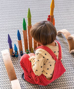 Child playing with the Grimm's large wooden building rollers in natural.