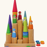 Grimm's large wooden building rollers in natural in a tray with coins, peg dolls and Grimm's forest pieces placed on them.