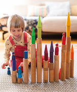 Child playing with the Grimm's large wooden building rollers in natural.
