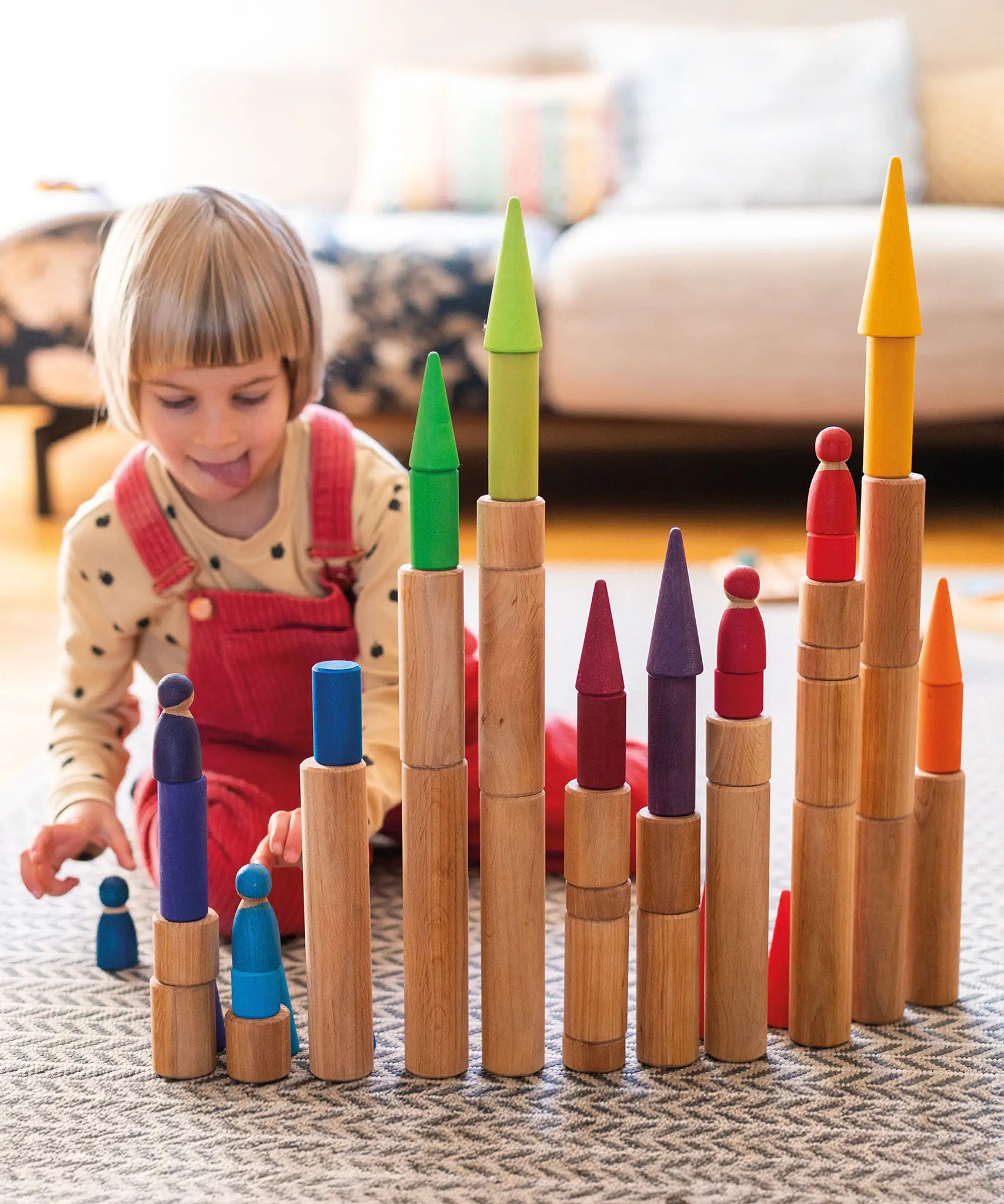 Child playing with the Grimm's large wooden building rollers in natural.