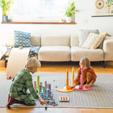 Children playing with Grimm's large building rollers pastel with other wooden toys.