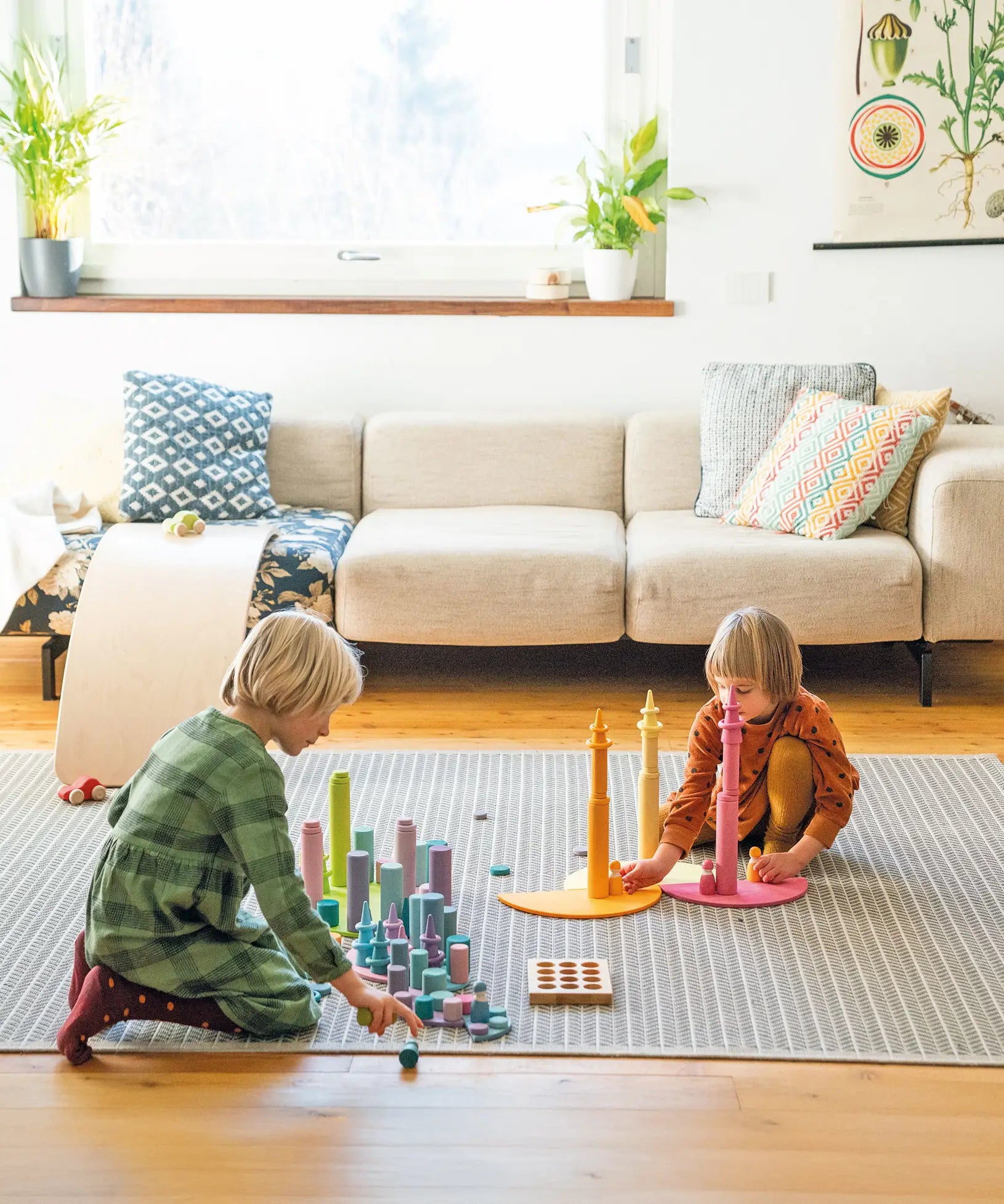 Children playing with Grimm's large building rollers pastel with other wooden toys.