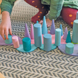 Child playing with Grimm's large building rollers in pastel , semi circles and forest pieces.