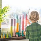 Child stacking Grimm's large building rollers pastel with forest pieces.