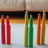 Grimm's large building rollers in bright rainbow colours with friends peg dolls stacked on top of them.