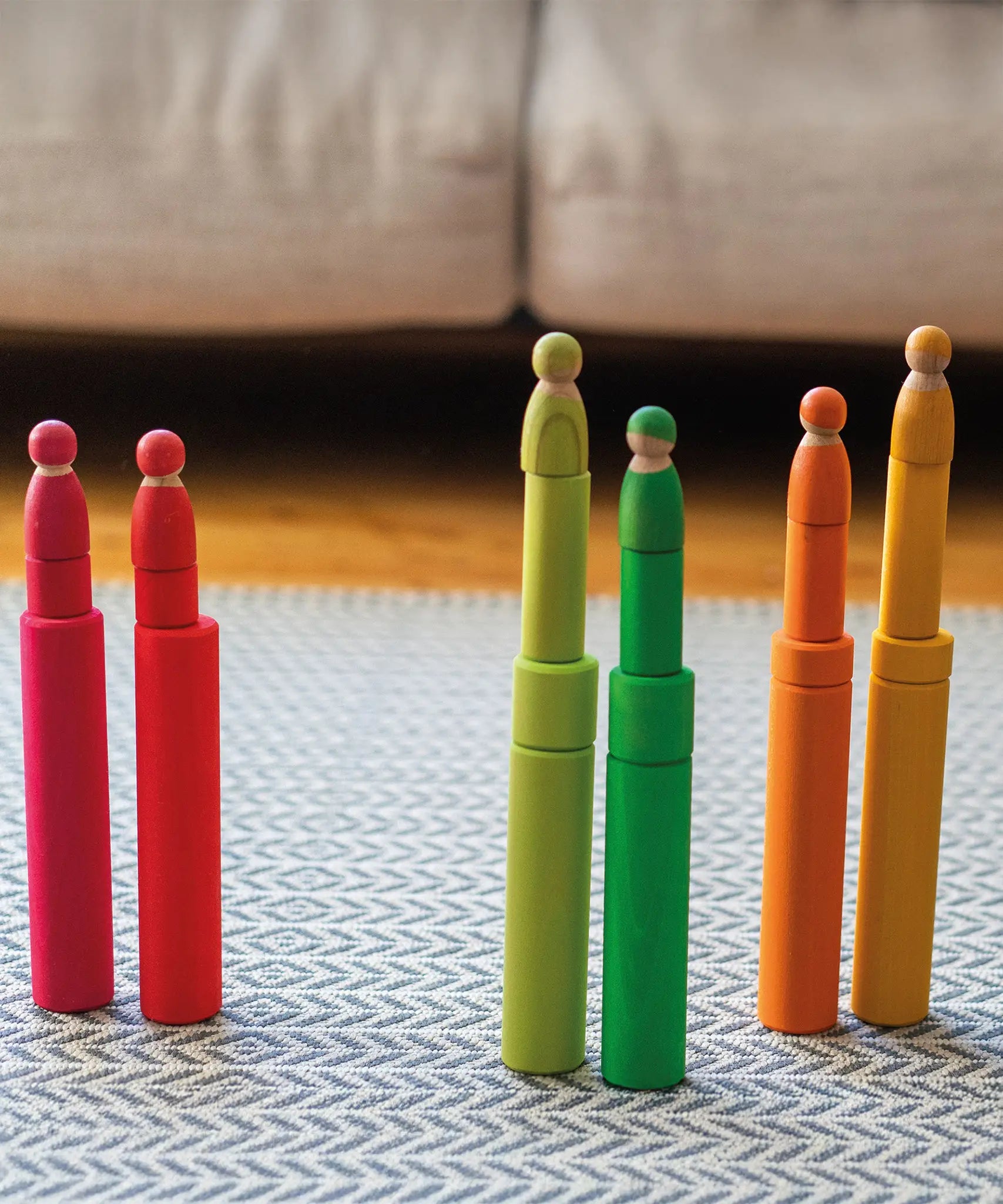 Grimm's large building rollers in bright rainbow colours with friends peg dolls stacked on top of them.