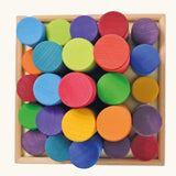Overhead view of the Grimm's large building rollers in bright rainbow colours in a wooden storage tray.