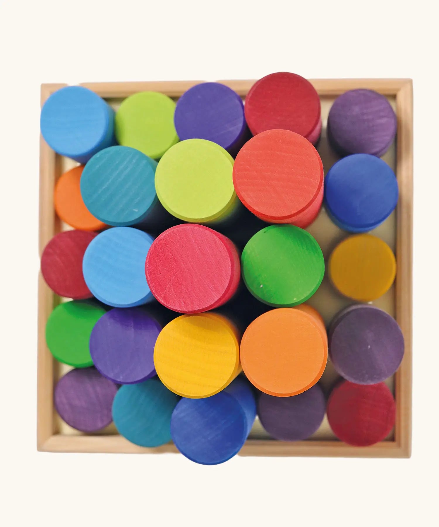 Overhead view of the Grimm's large building rollers in bright rainbow colours in a wooden storage tray.