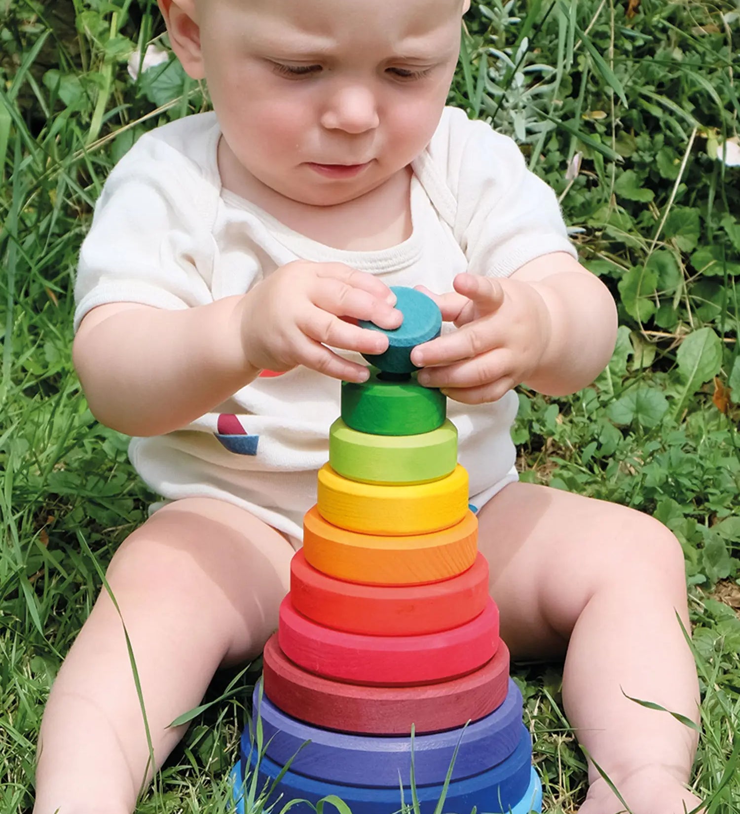 Baby playing with the Grimms large conical tower in a Grimm’s World of Numbers palette