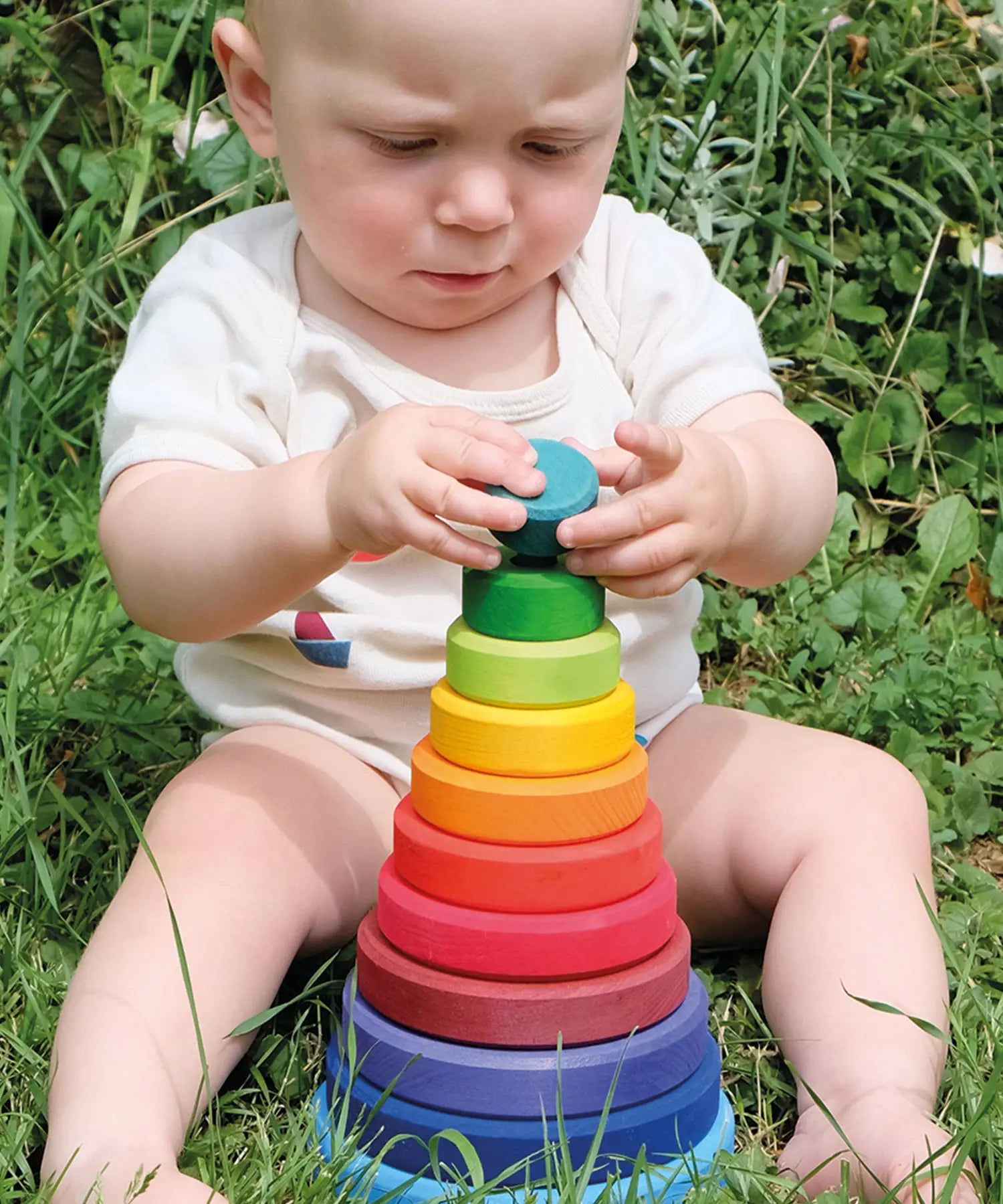 Baby playing with the Grimms large conical tower in a Grimm’s World of Numbers palette