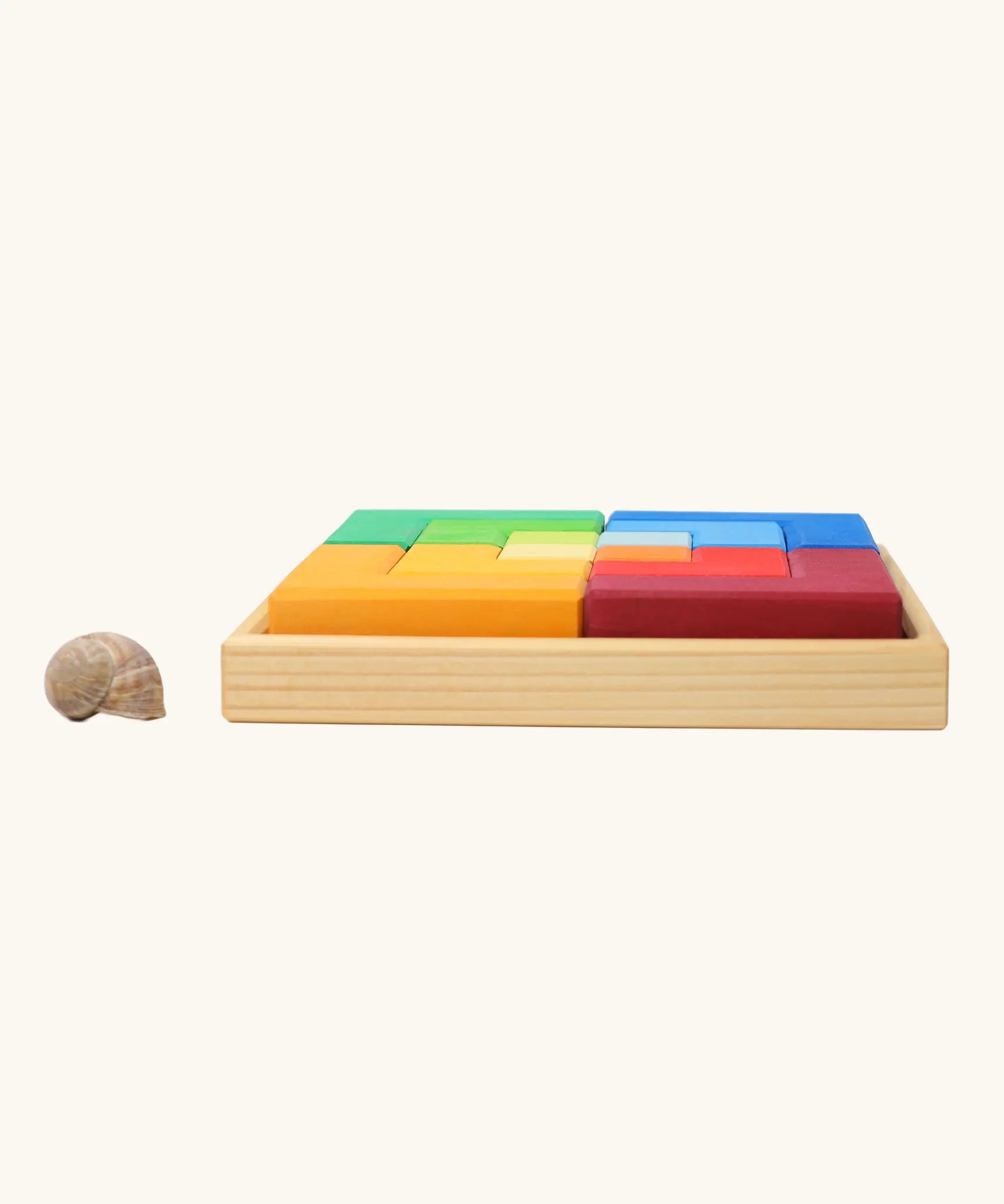 Side view of the Grimm's large creative puzzle square wooden toy in a wooden storage display tray. 