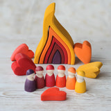 Grimms handcrafted wooden large fire set in a display with heart shaped pieces and peg dolls in matching warm colours