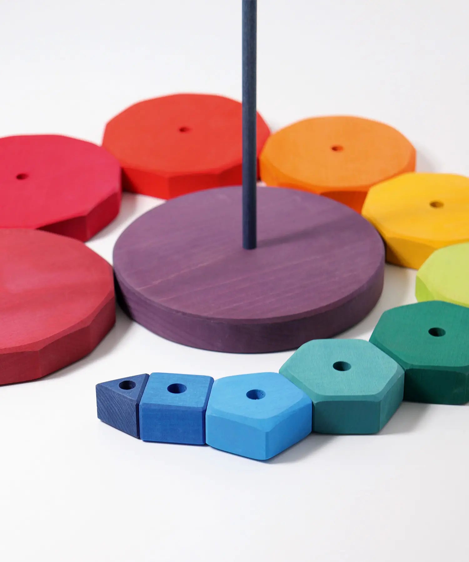 Loose Grimms geometric wooden blocks in a shape of a swirl around the purple base