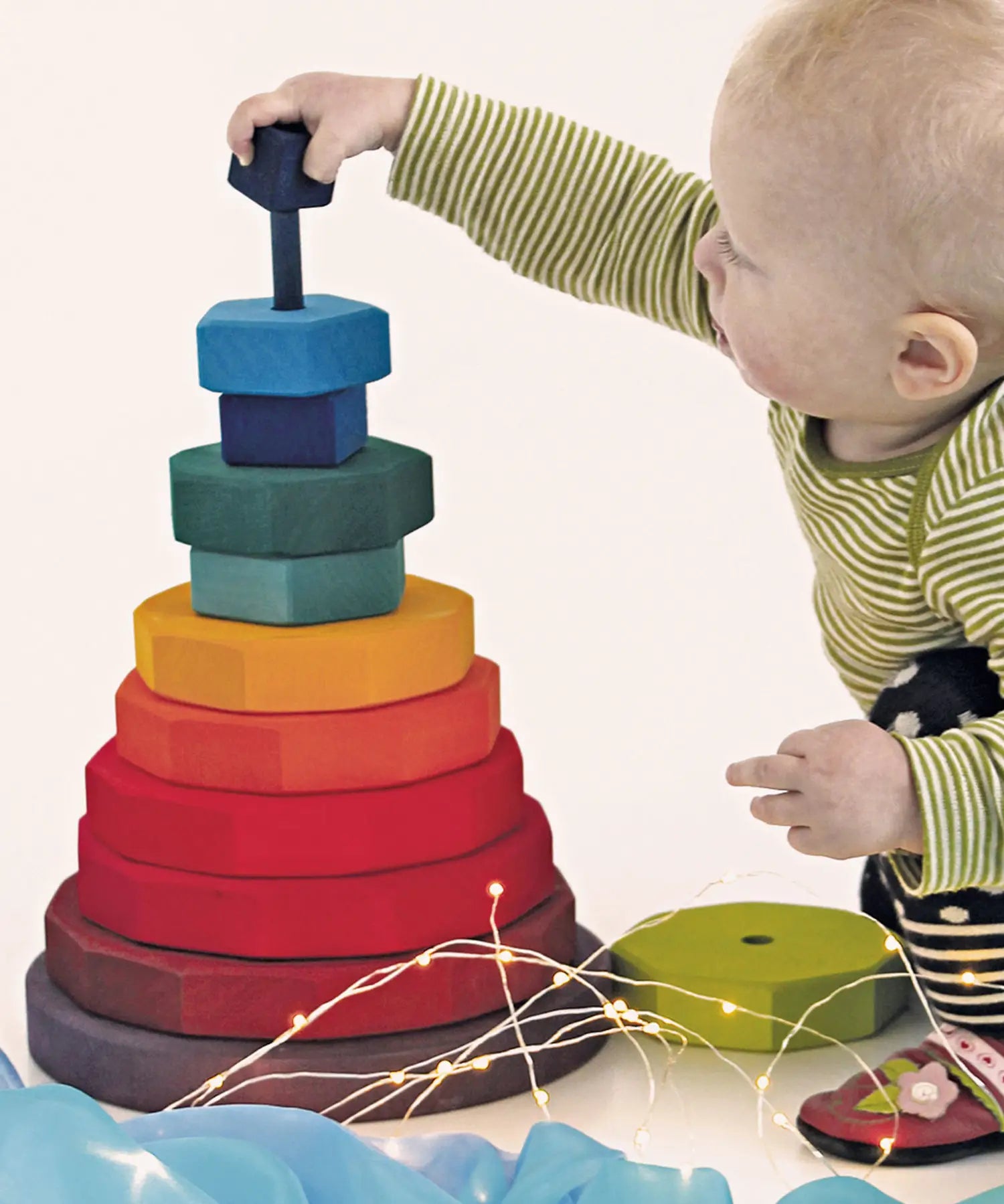 Child threading the blocks from the Grimms large geometric tower stacker toy