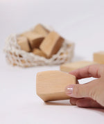 Adult's hand holding a block from the Grimm's large wooden natural building blocks set.