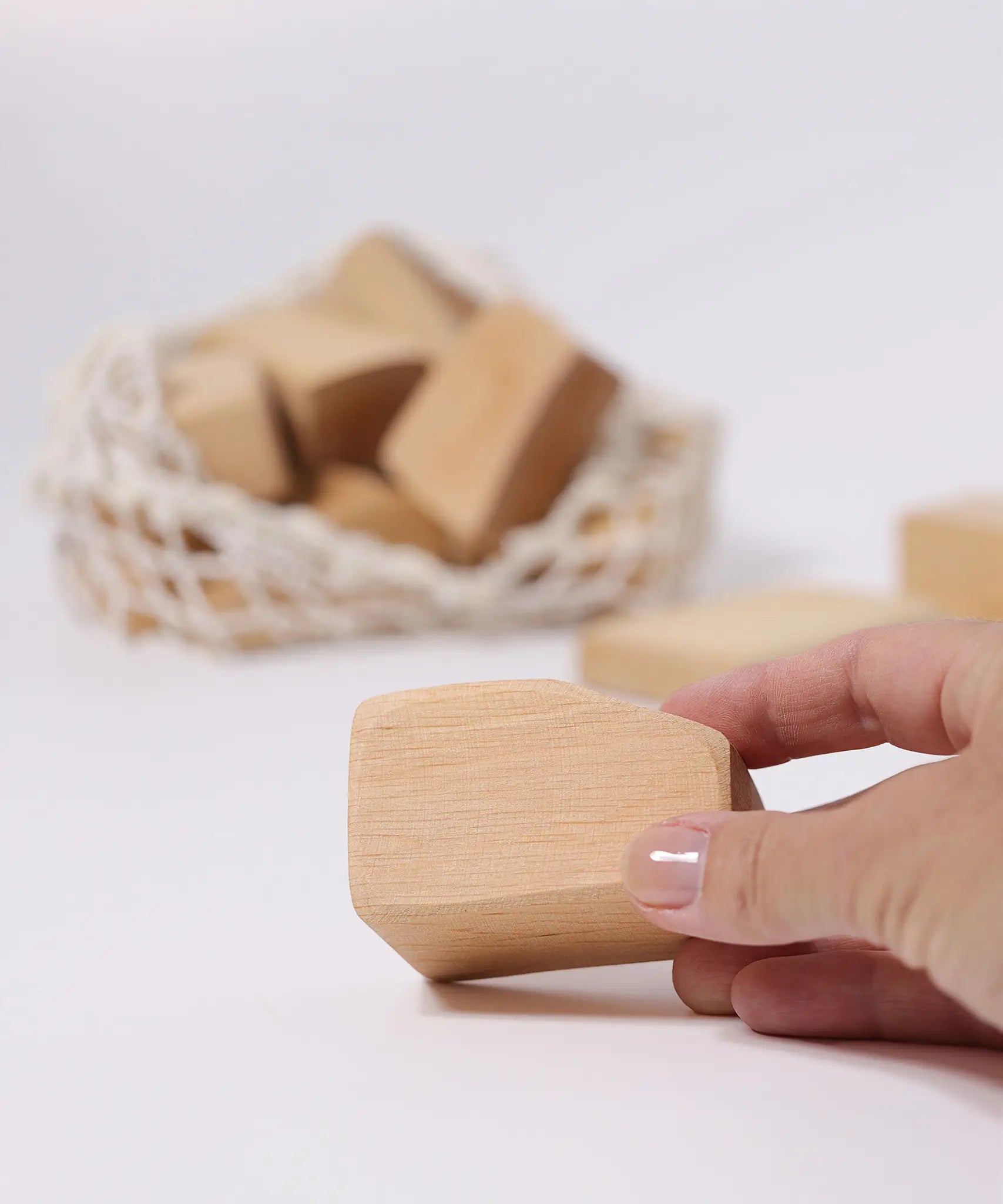 Adult's hand holding a block from the Grimm's large wooden natural building blocks set.