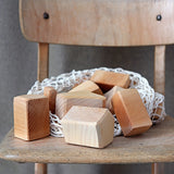 Grimm's large wooden natural building blocks set placed on a wooden chair.
