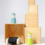 Grimms large wooden natural building boxes stacked with a wooden car inside and peg dolls on top