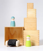 Grimms large wooden natural building boxes stacked with a wooden car inside and peg dolls on top