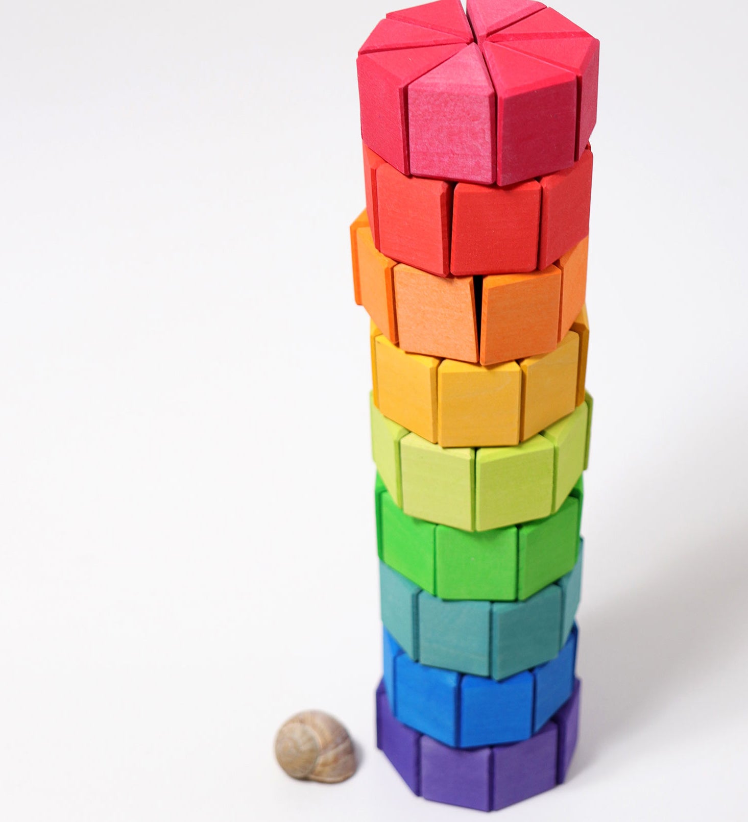 The triangular shaped wooden blocks from the Grimm's Large Octagon Puzzle Set stacked up to create a tower.