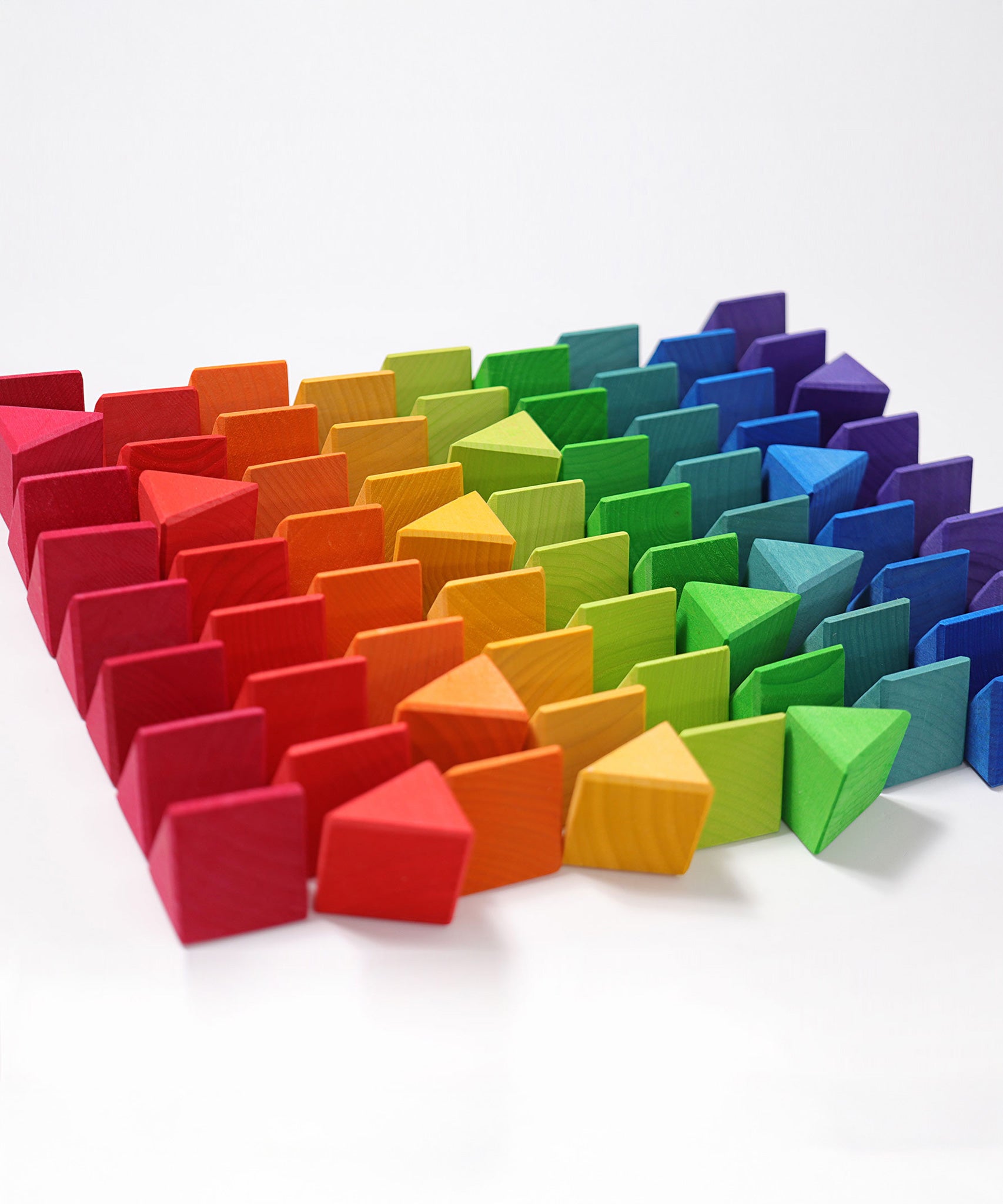 The triangluar shaped blocks from the Grimm's Octagon Puzzles paid out and lined up on a flat white surface. 
