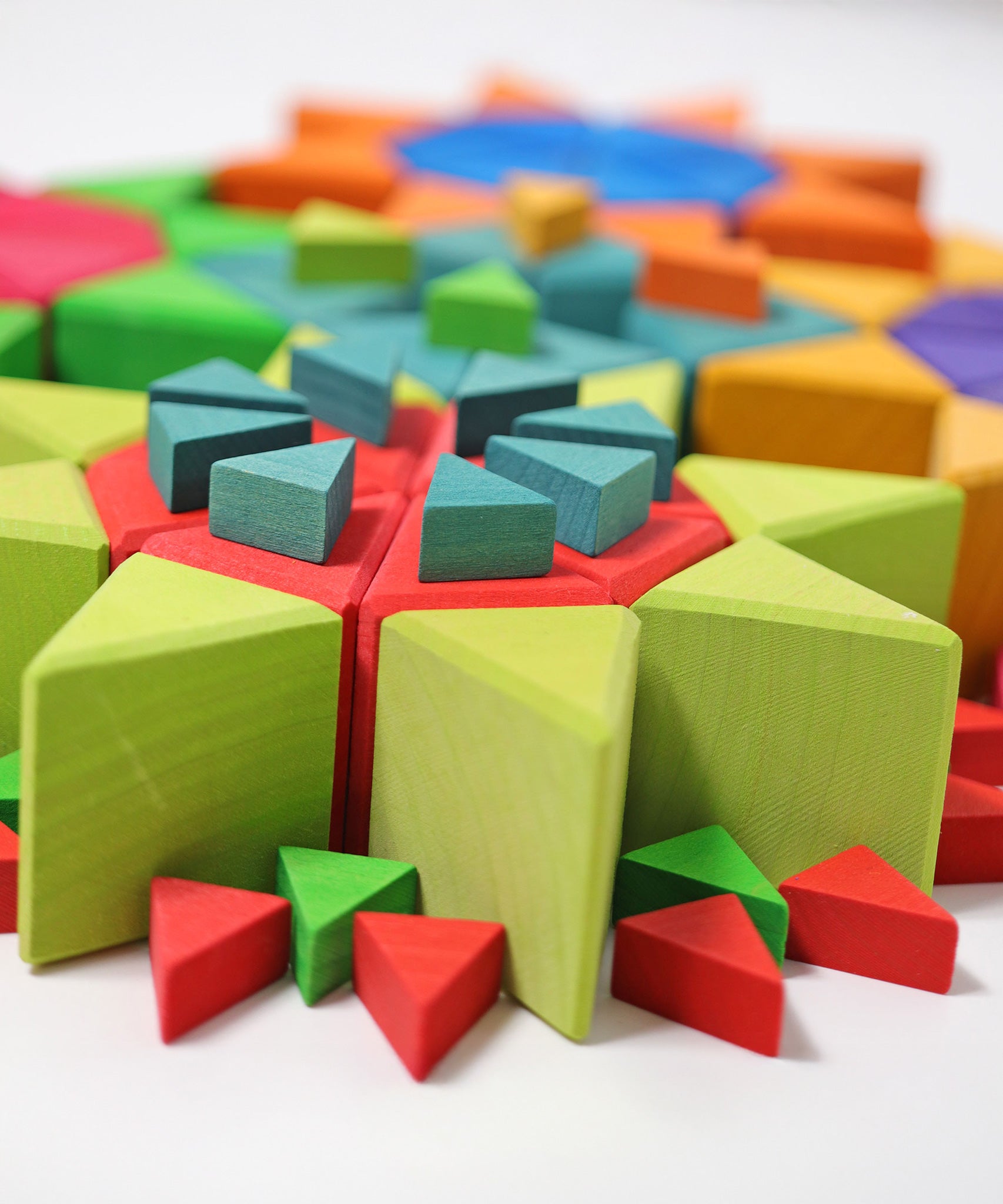 A close up, side view of the triangular shaped blocks from the Grimm's Octagon Puzzles used to created flower shapes withe the large set used for the flowers and the smaller sets used for the stems and details. 