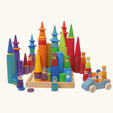 Grimm's large building rollers in bright rainbow colours in a wooden storage tray with other Grimm's wooden toys, friends peg dolls, rings, cars and forest cone shapes pieces.