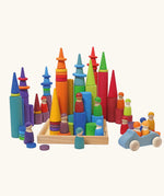 Grimm's large building rollers in bright rainbow colours in a wooden storage tray with other Grimm's wooden toys, friends peg dolls, rings, cars and forest cone shapes pieces.