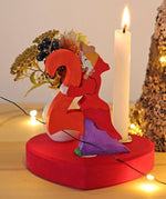 Grimm's Large Red Heart Celebration Ring with a number 2 decorative figure, a decorative vase and a candle. 