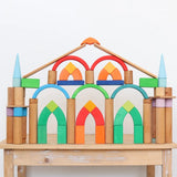 Grimm's Romanesque building blocks and natural rollers used to create a structure on a wooden table. 