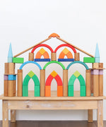 Grimm's Romanesque building blocks and natural rollers used to create a structure on a wooden table. 