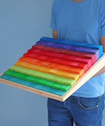 Adult holding a Grimms large stepped wooden counting blocks in Grimm’s World of Numbers palette 