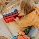 Grimms large stepped wooden counting blocks in Grimm’s World of Numbers palette arranged in the frame by an adult