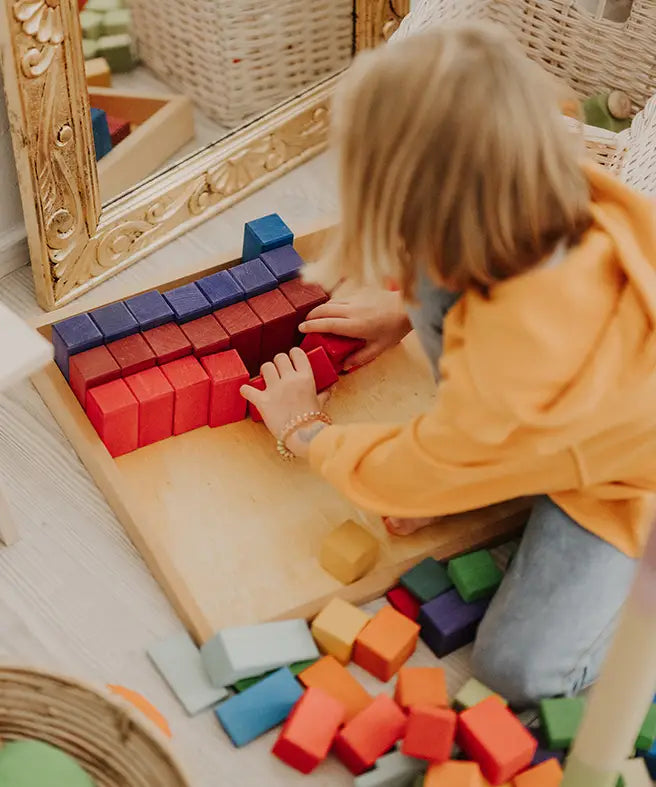 Grimms large stepped wooden counting blocks in Grimm’s World of Numbers palette arranged in the frame by an adult