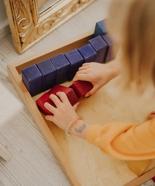 Adult sorting individual blocks from the Grimms large stepped wooden counting blocks
