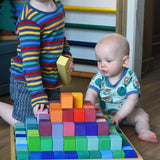 Grimm's large stepped pyramid coloured wooden block set played with by a young child an baby in the Babipur playroom.