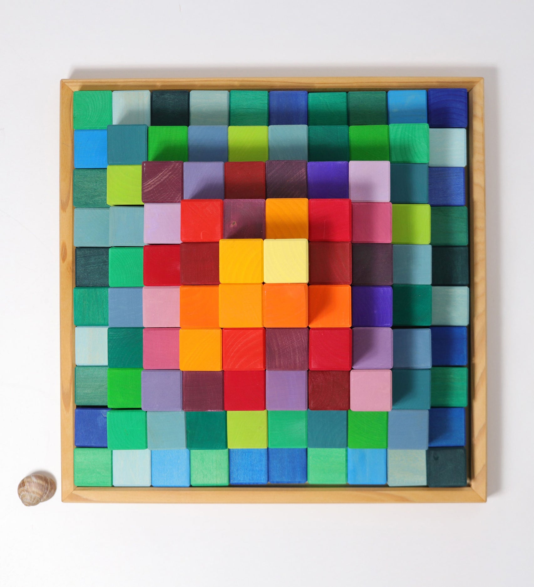 An overhead view of the Grimm's rainbow coloured Large Stepped Pyramid wooden toy building block set in the wooden storage tray. These Grimm's toys are part of a wide range of wooden toys available here at Babipur. 