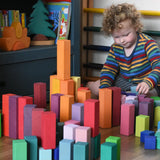 Grimm's large stepped pyramid coloured wooden blocks being lined up by a child. 