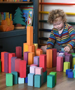 Grimm's large stepped pyramid coloured wooden blocks being lined up by a child. 