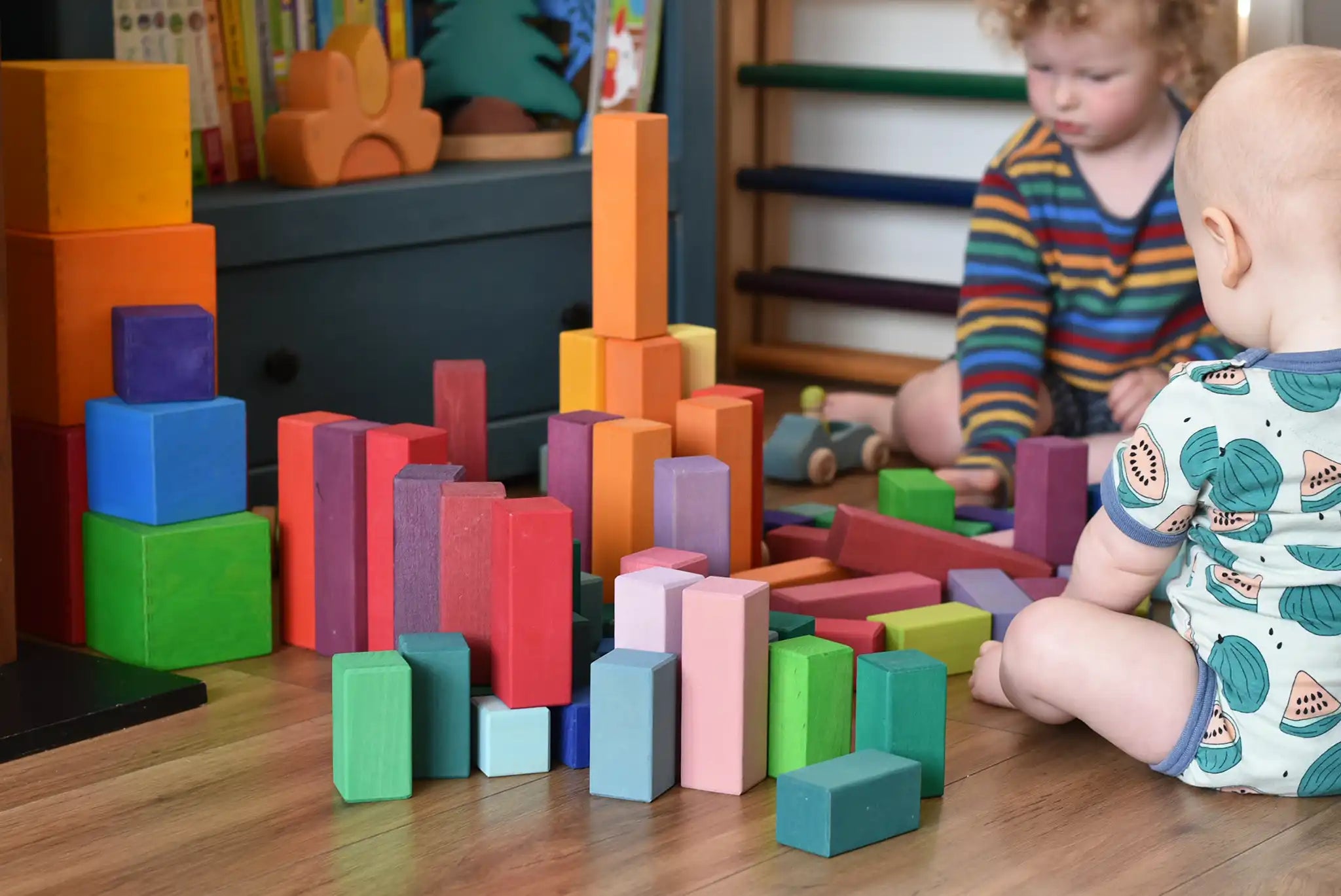 Grimm's large stepped pyramid coloured wooden block set played with by a young child an baby in the Babipur playroom.