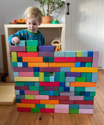 Grimm's large stepped pyramid coloured wooden block set used to create a large wall like structure by a child.