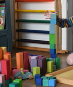 Grimm's large stepped pyramid coloured wooden blocks being stacked by a child in the Babipur playroom.