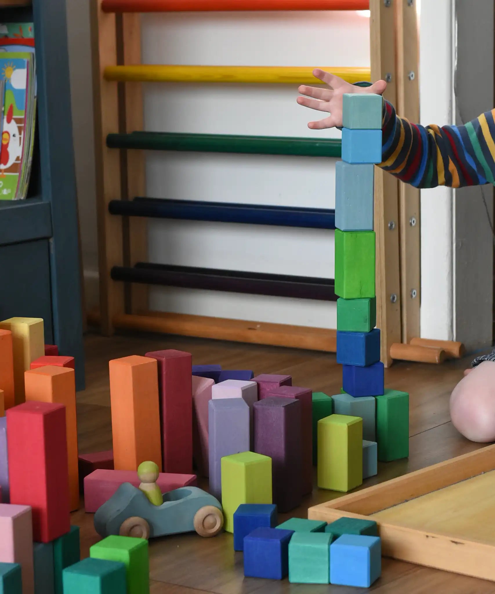 Grimm's large stepped pyramid coloured wooden blocks being stacked by a child in the Babipur playroom.