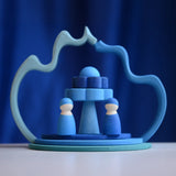 2 Grimms wave shaped pieces leaning on each other making a display with 2 blue peg dolls and other loose pieces 
