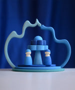 2 Grimms wave shaped pieces leaning on each other making a display with 2 blue peg dolls and other loose pieces 