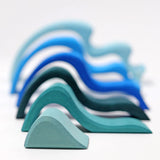 Pieces from the Grimms large wooden blue water wave set lined up from small to large