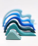 Pieces from the Grimms large wooden blue water wave set lined up from small to large