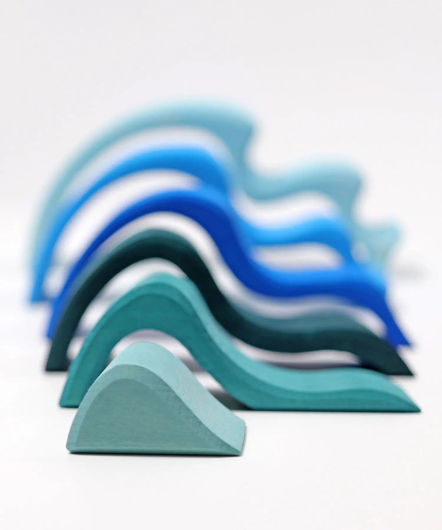 Pieces from the Grimms large wooden blue water wave set lined up from small to large